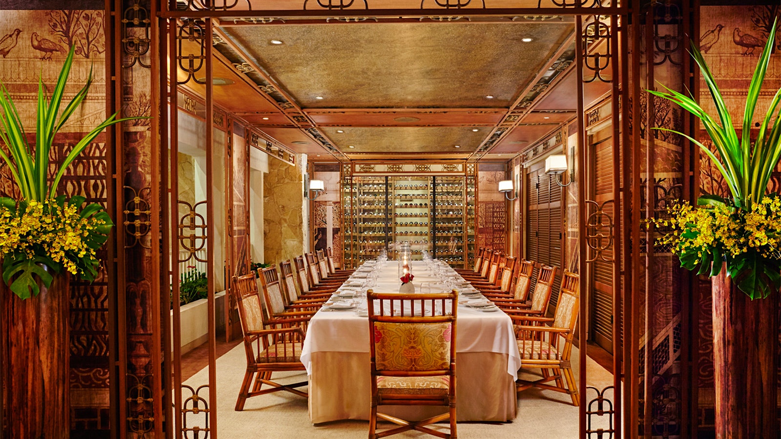 Wine room at La Mer, with wooden chairs, wooden window shutters and a wall of stacked wine bottles